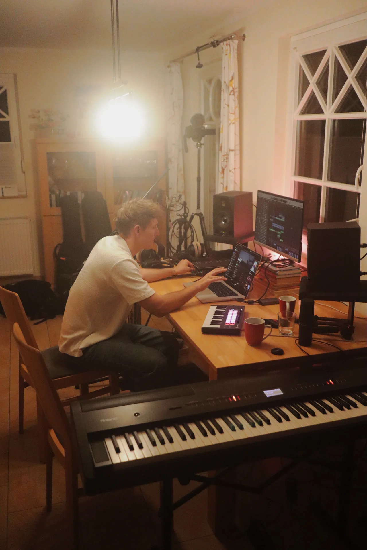 Toni im Home-Studio am Laptop, umgeben von Keyboard und Studiomonitoren